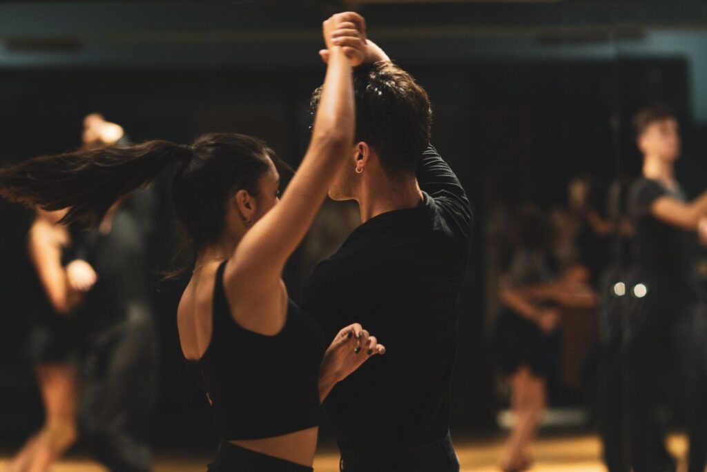 A couple elegantly performing tango inside a dance studio with onlookers.